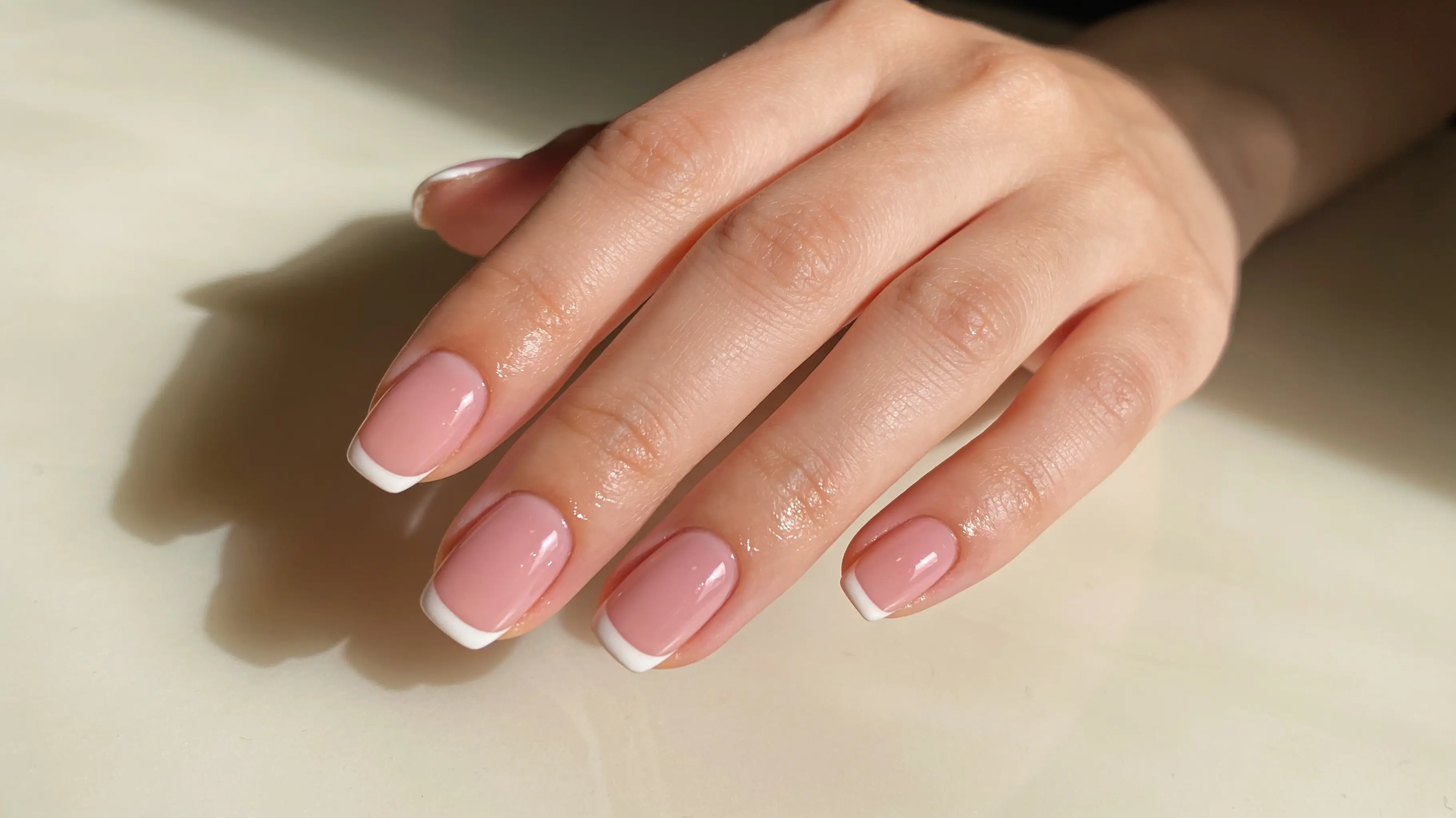 La stessa mano dopo l’appuntamento, con unghie sagomate di media lunghezza in gel milk blush